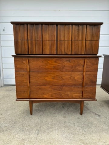 Wooden dresser with multiple drawers against a white wall.