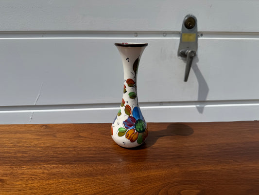 Decorative vase with colorful designs on a wooden surface and white wall background