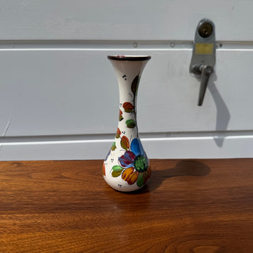 Decorative vase with colorful designs on a wooden surface and white wall background
